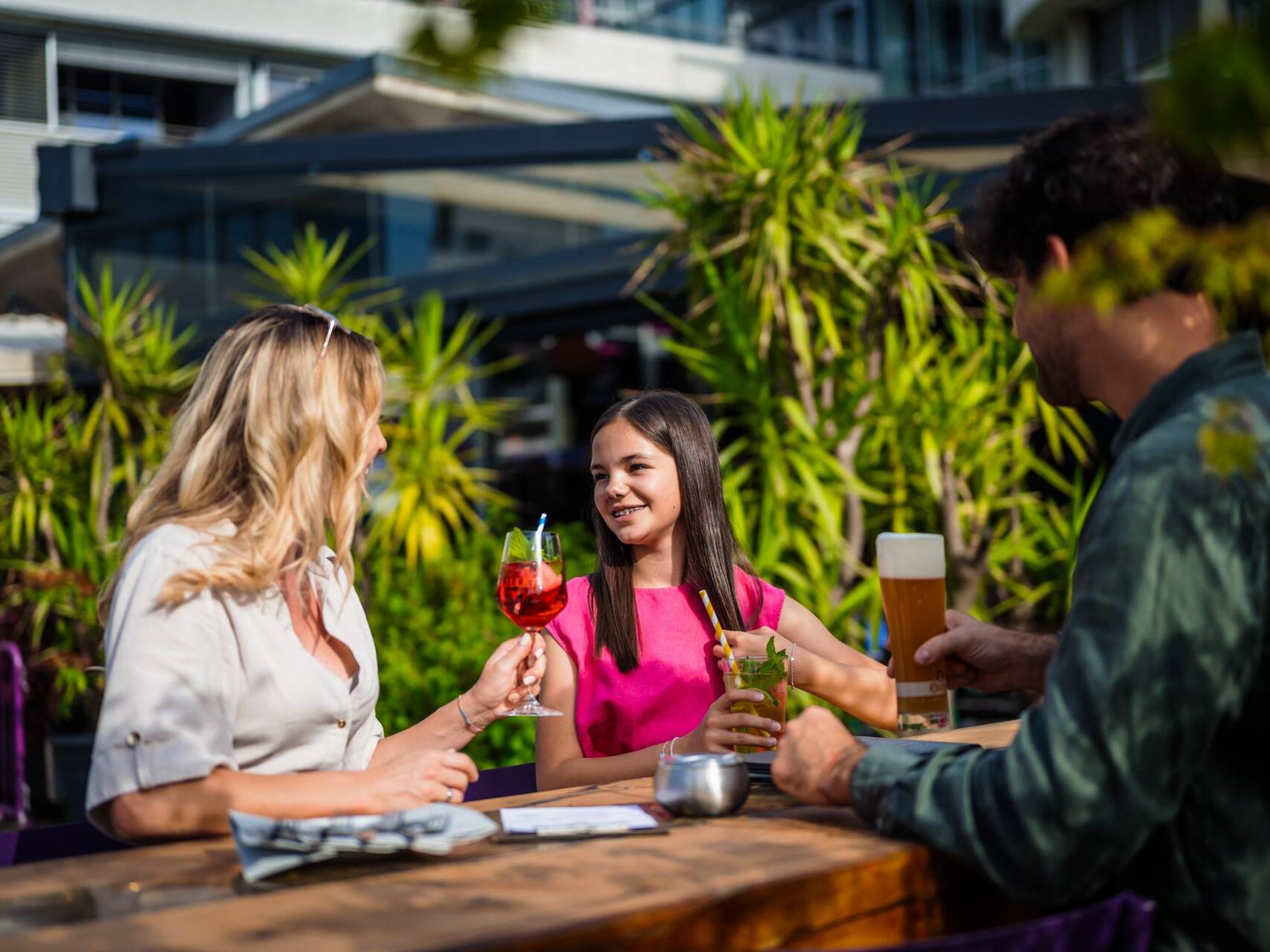 Drei Freunde mit Getränken auf einer Hotelterrasse