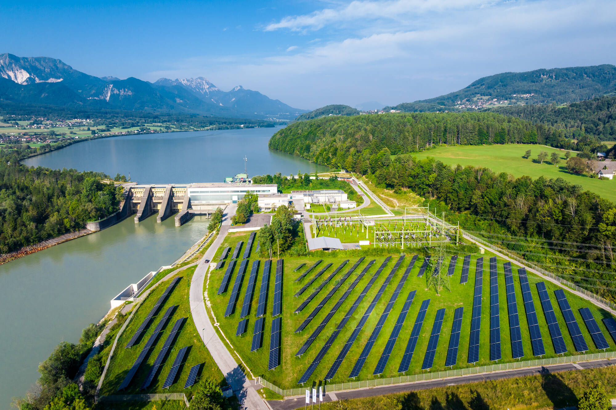 Luftaufnahme eines Flusskraftwerks mit Photovoltaikanlage im Tal