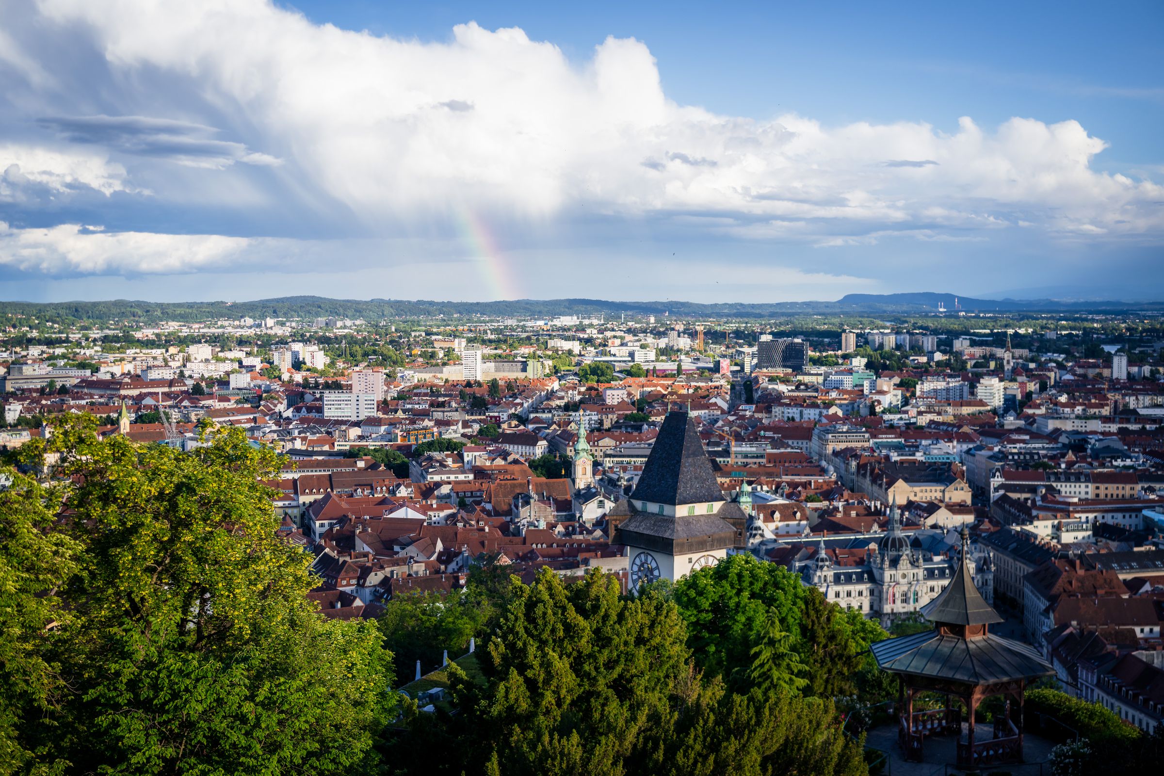 Blick vom Schlossberg auf den Grazer Uhrturm und die Altstadt von Graz mit Regenbogen – Tourismusfotografie
