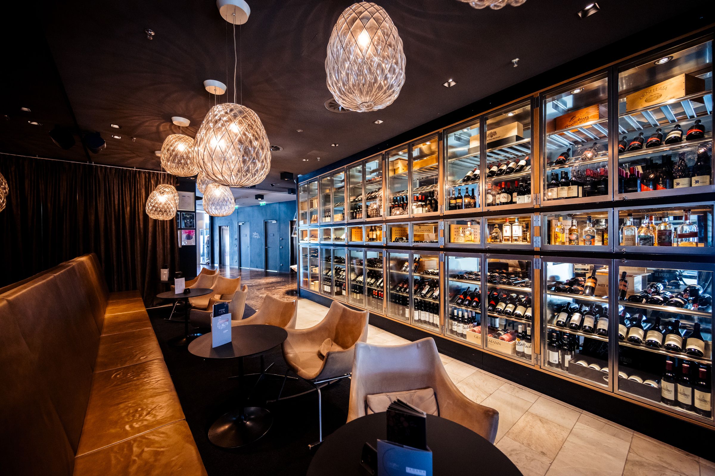 Hotelbar mit beleuchteter Weinwand, Ledersesseln und Designerleuchten – Interiorfotografie